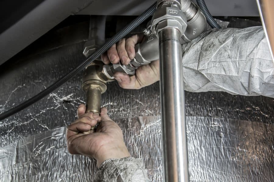 Handen werken aan metalen leidingwerk